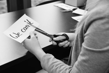Frau zerschneidet "We can't" zu "We can" - Motivation und Erfolg im Business durch Zusammenhalt im Team