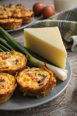 Muffins with scrambled eggs, cheese, bacon, potato and red pepper. Breakfast concept. Gray, rustic wooden background.
