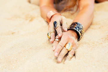 Woman's hands with expressive jewelry in sand