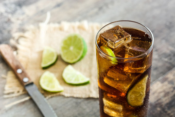 Cuba libre. Cocktail with rum, lime and ice on wooden table