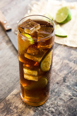 Cuba libre. Cocktail with rum, lime and ice on wooden table