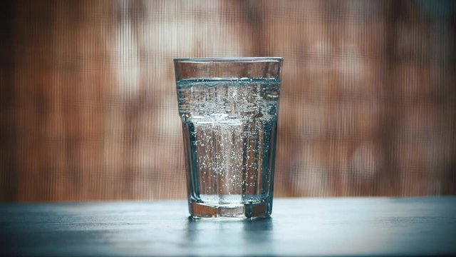 Pouring Fresh Cold Fizzy Mineral Water Into Drinking Glass On The Table