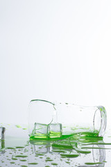 ​broken glass ice hand and green water on white background