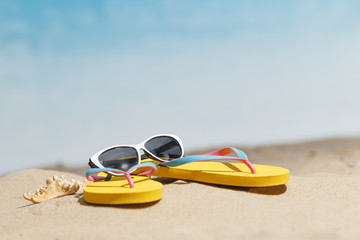 Flip flops, sunglasses and accessiores on sandy beach. holidays background. Copy space.