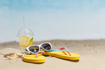 Flip flops, sunglasses and accessiores on sandy beach. holidays background. Copy space.