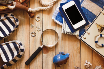 Striped slippers, towel, piggy bank, phone and maritime decorations, wooden background