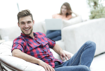 happy young man sitting in a big chair on blurred background