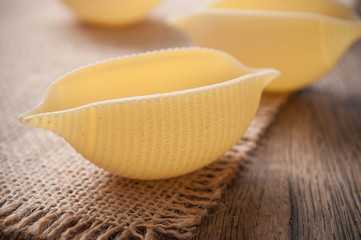 closeup of shaped seashell pasta on wooden background