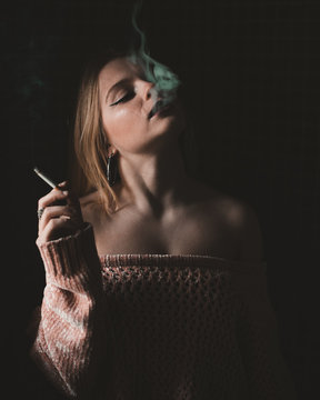 Woman smoking cigarette against black background