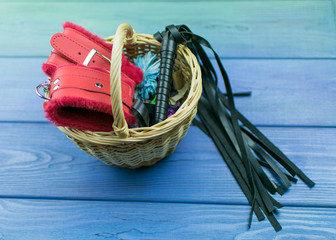 Handcuffs and a whip for BDSM in the basket. Accesories for sexual games.