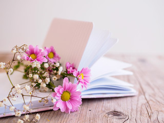 Rosa und weiße Blumen auf einem Notizbuch auf einem grauen Holztisch. Weißer Hintergrund, Textfreiraum, Frühling.