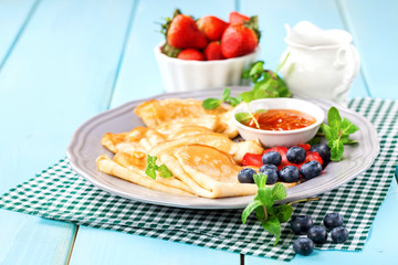 Pancakes with jam and berries on a table. Selective focus. Copy space.