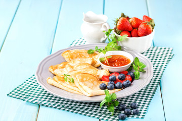 Pancakes with jam and berries on a table. Selective focus. Copy space.