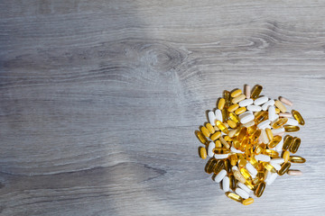 Bunch of Omega 3 tablets and capsules, carnitine, creatine, fat burners, BCAA or testosterone booster. Sports medical vitamins and preparations on a wooden table.