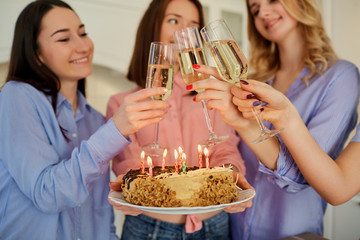 A cake with candles for the birthday in the hands of the girls close-up. Birthday party.