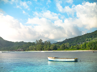 Small colorful boat anchored off a Seychelles beach with distant shore