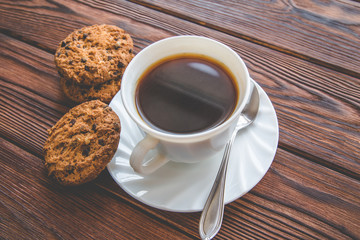 A cup of hot coffee stands on a wooden table 