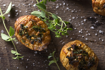 Accordion baked potatoes with different herbs and sea salt on wood