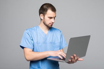 The doctor staring on the laptop isolated on gray background