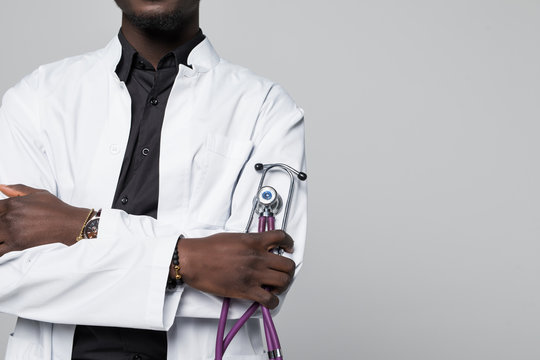 Portrait of handsome Afro American doctor with sthethoscope in white coat looking at camera, isolated on gray background