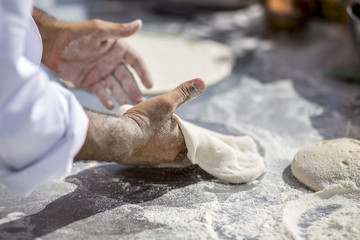 Le mani di un pizzaiolo napoletano che lavorano la pasta