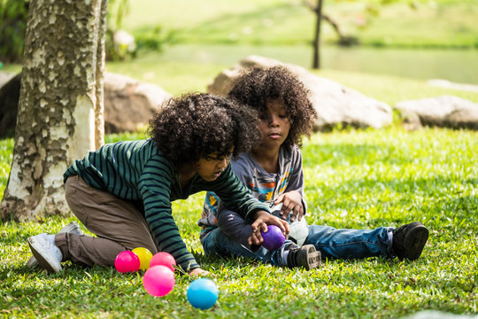 Kids playing balls together. Group of children sitting on grass in a park.