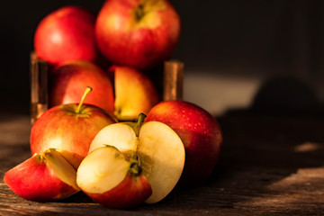 Apples whole and cut in halves on wooden surface