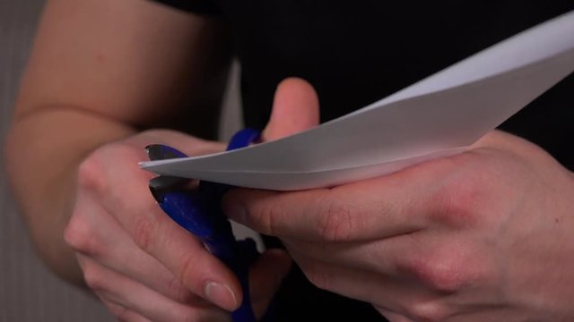 An artist cuts paper for origami in a living room - closeup