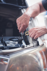 Action of man hands using spanner remove car battery terminals to change the new one, car fixing and maintenance service concept.