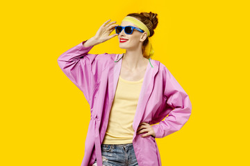 Young woman on a yellow background and pink coat and sunglasses. Colour obsession concept.  Minimalistic style. Stylish Trendy