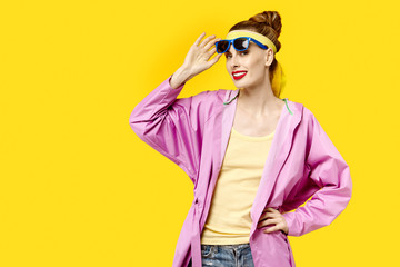 Young woman on a yellow background and pink coat and sunglasses. Colour obsession concept.  Minimalistic style. Stylish Trendy