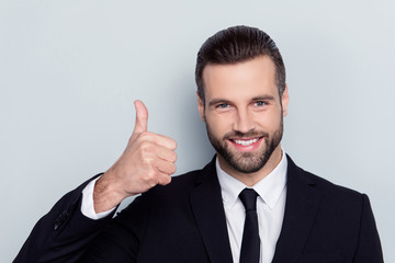 Close up portrait of handsome confident cheerful  excited positive emotional with toothy beaming smile agent employer staff with modern hairstyle demonstrating thumb-up isolated on gray background