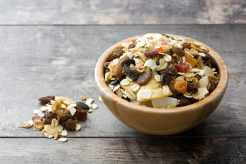 Muesli and dried fruit in wooden bowl on wooden table. 