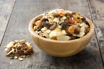 Muesli and dried fruit in wooden bowl on wooden table. 