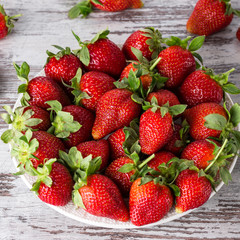 strawberries in a plate on a gray wooden table, fresh strawberries on a table, seasonal fruits