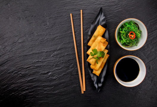 Asian food with spring rolls, seaweed and chopsticks