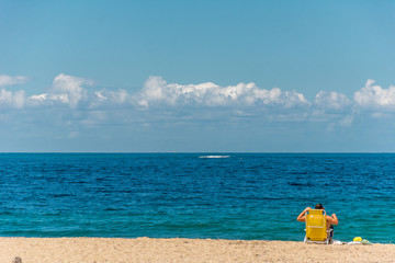 Fototapeta na wymiar Tourist on the beach sitted on his yellow chair