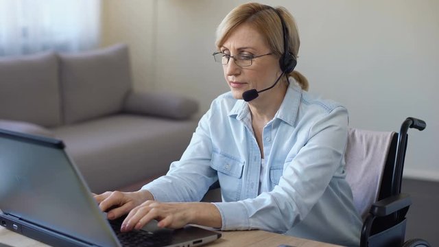 Call-center female operator working with client typing on laptop, disabled woman