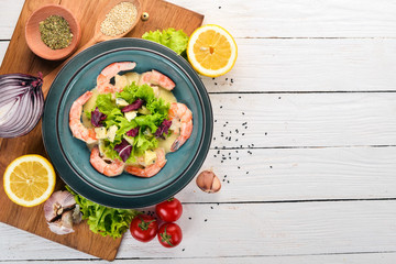 Royal prawns in creamy sauce and cheese. Seafood on a plate. Top view. On a white wooden background. Copy space.