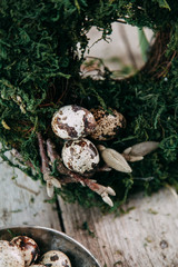 Spring Easter wreath with quail eggs, decoration in the interior and on the head. Compositions of moss and greenery on a wooden background