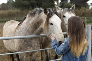 Young woman giving affection to some horses.