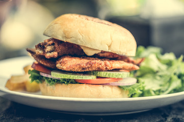 street food fishburger with fish cutlet and vegetables on white plate.