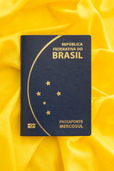 Brazilian passport on yellow fabric representing the Brazilian flag. Important document for trips abroad.