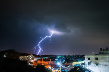 Heavy storm at night with dramatic clouds and thunderbolt lightning to the city.