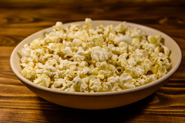 Ceramic plate with popcorn on wooden table