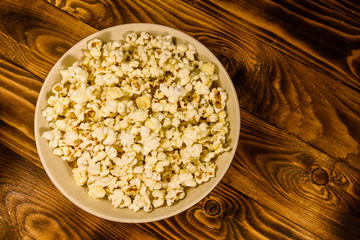 Ceramic plate with popcorn on wooden table. Top view