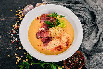 Pea soup with bacon and croutons. Top view. On a wooden background. Copy space.