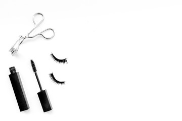 Cosmetics and tools for voluminous lashes. Mascara, false eyelashes, eyelash curler on white background top view space for text