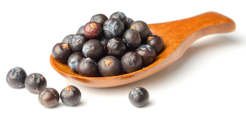 dried juniper berries in the wooden spoon, isolated on white