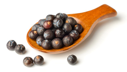 dried juniper berries in the wooden spoon, isolated on white